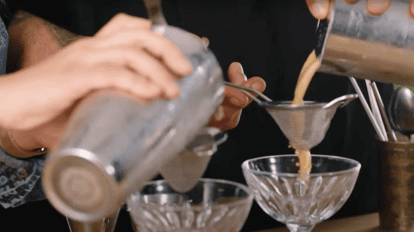 Double straining an espresso martini with a Hawthorne strainer and fine mesh strainer