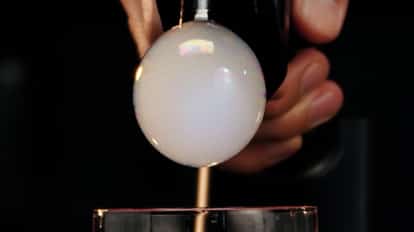 Cocktail bubble gun releasing a bubble on top of a Cosmopolitan cocktail.