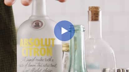 A bottle of Absolut Citron vodka among glassware.
