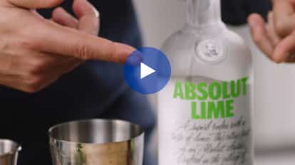 Absolut Lime bottle beside metal cocktail shaker and jigger