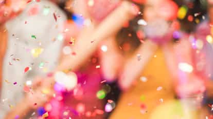 Colorful confetti falling over blurred people celebrating at a party.