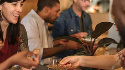 Group of people sharing brunch plates and cocktails at a wooden table