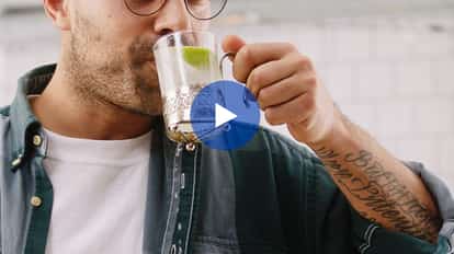 Rico sipping a clear drink with a lime wedge from a glass mug in an ornate metal holder