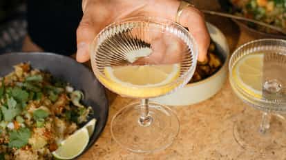 Two coupe glasses with lemon-garnished cocktails on a table.