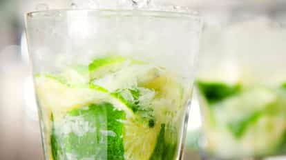 A smash cocktail with muddled lime and crushed ice in a rocks glass.