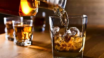 Irish Whiskey being poured into a Rocks Glass filled with Ice Cubes.
