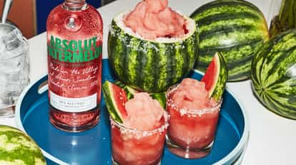 Absolut Watermelon frozen vodkarita next to a bottle of Absolut Watermelon and fresh watermelon.