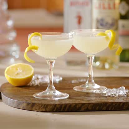 Two Corpse Reviver No 2 cocktails garnished with lemon zest with half a lemon in the background