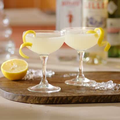 Two Corpse Reviver No 2 cocktails garnished with lemon zest with half a lemon in the background