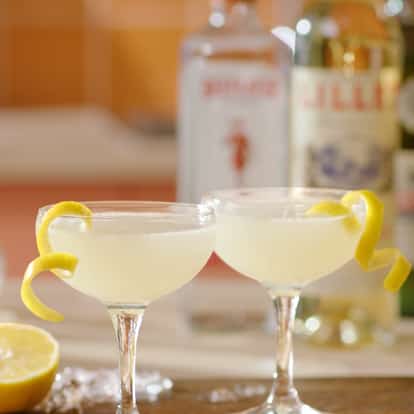 Two Corpse Reviver No 2 cocktails garnished with lemon zest with half a lemon in the background