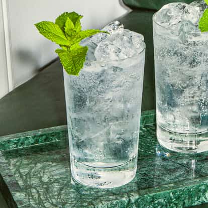 Malibu St Lawrence Lemonade in zwei hohen Gläsern mit Crushed Ice und Minze, serviert auf einem grünen Marmortablett.