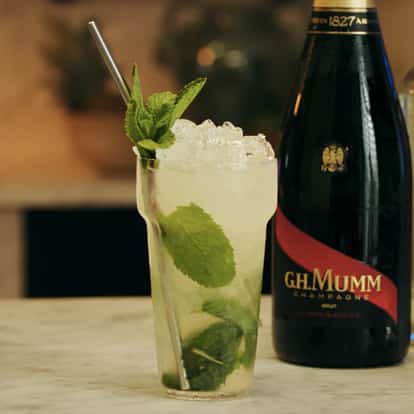 Royal Mojito cocktail, garnished with a mint sprig next to a bottle of G.H. MuMM.