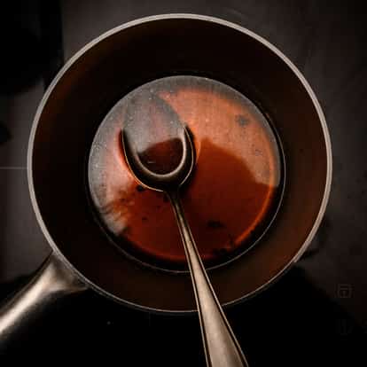 Beef Consomme in a saucepan with a spoon on a stovetop