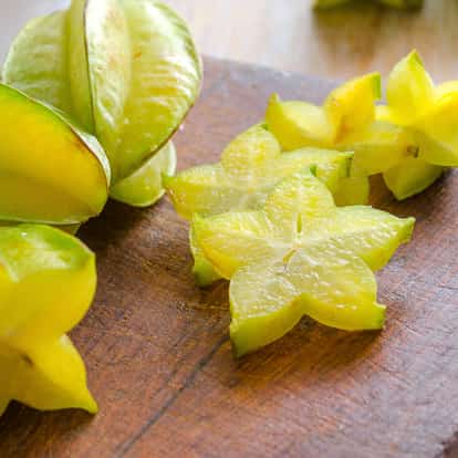Carambola sliced and whole on a wooden cutting board