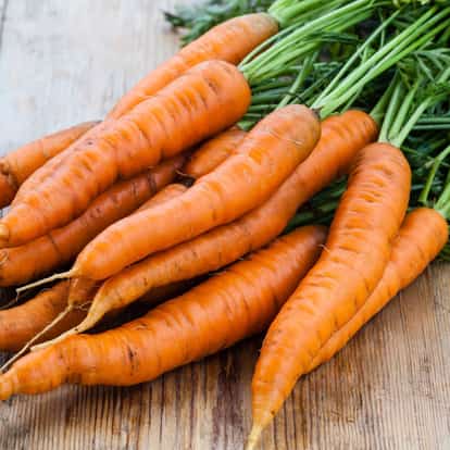 Carrot bunch with greens on a wooden surface