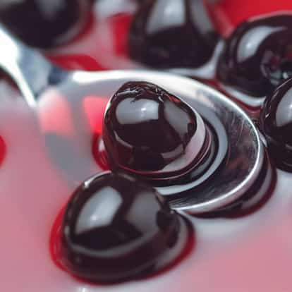 Cherry syrup with whole cherries on a spoon