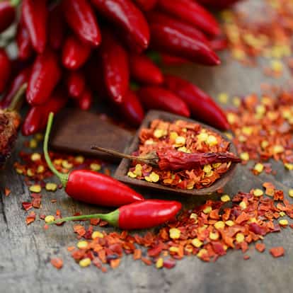 Chilean Hot Pepper whole and crushed on a wooden surface