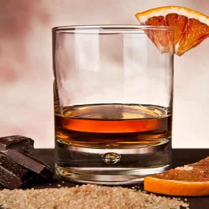 Chocolate And Orange Liqueur served in a rocks glass with orange slice on rim and chocolate pieces on slate