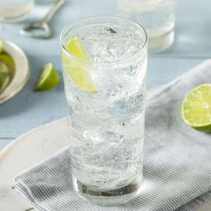 Citrus Tonic Water served in a tall highball glass with a lime wedge on a grey striped napkin.