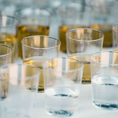 Goldschlager Liqueur in plastic tasting cups on white surface