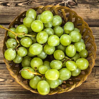 Grapes in a woven basket on a wooden background