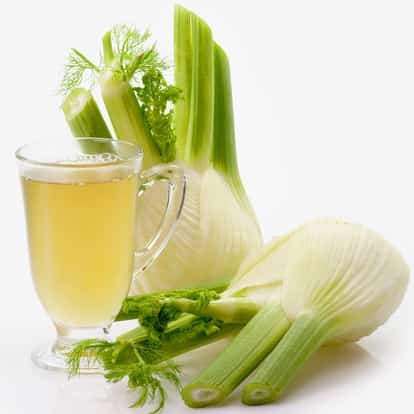 Homemade Fennel Cordial in a clear glass mug with fennel bulbs on white background