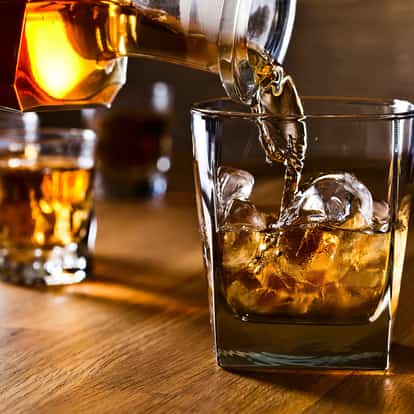 Irish Whiskey poured into a rocks glass with ice on a wooden surface