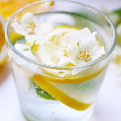 Jasmine Liqueur in a chilled rocks glass with ice, a lemon twist and jasmine flowers