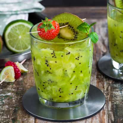 Kiwi Puree in a rocks glass garnished with a kiwi slice, strawberry and mint sprig