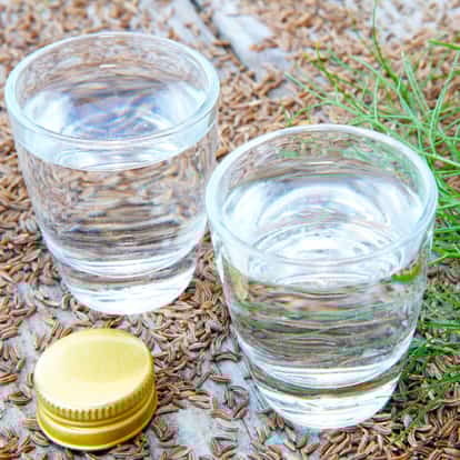 Kümmel in two shot glasses on caraway seeds with a bottle cap