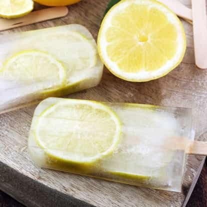 Lemon Popsicle on a wooden board with a halved lemon and wooden sticks
