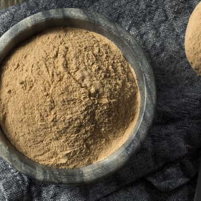Lucuma powder in a stone mortar on woven cloth with a wooden spoon