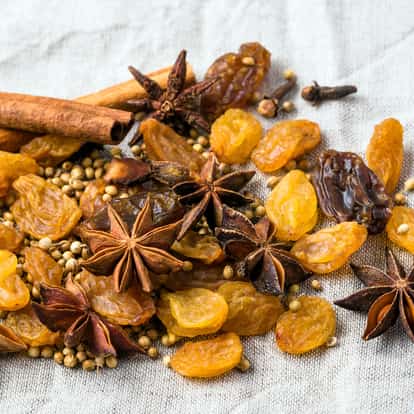 Mulled spices with star anise, cinnamon sticks coriander seeds and raisins on linen background