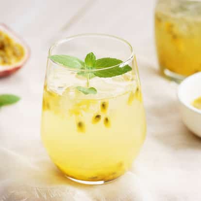 Passion fruit Syrup in a stemless glass with crushed ice, passion fruit seeds and a mint sprig