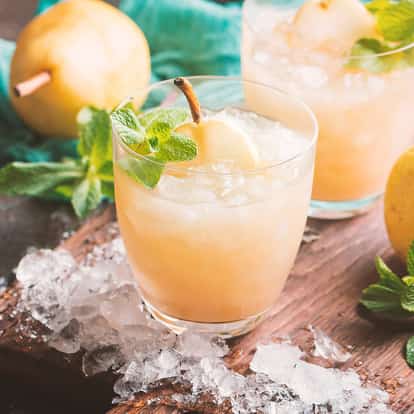 Pear Essence cocktail in a rocks glass with crushed ice and a pear slice and mint garnish.