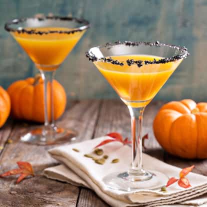 Pumpkin Puree in a martini glass with sugar rim on a wooden table with whole pumpkins and pumpkin seeds
