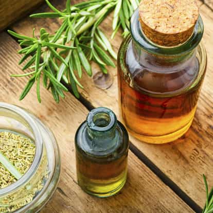 Rosemary syrup in small glass bottles with rosemary sprigs on a wooden board