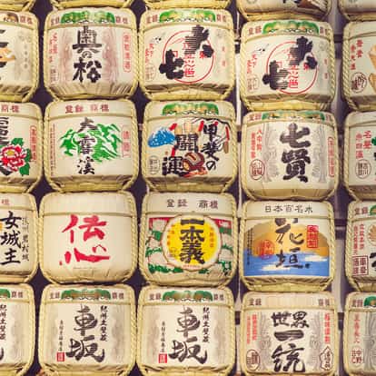 Sake stacked barrels with Japanese labels and woven rope bindings on a wall