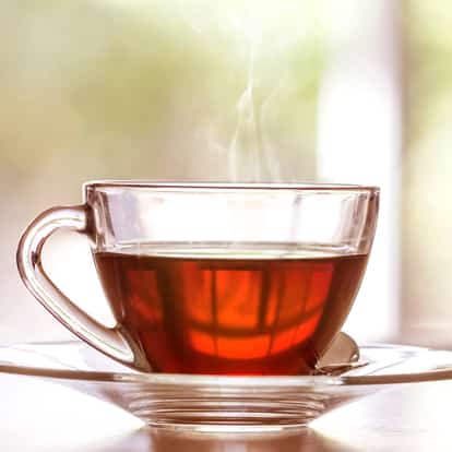Tea (hot) in a glass teacup on a saucer with steam rising