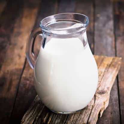 Whole Milk in a glass pitcher on a wooden board