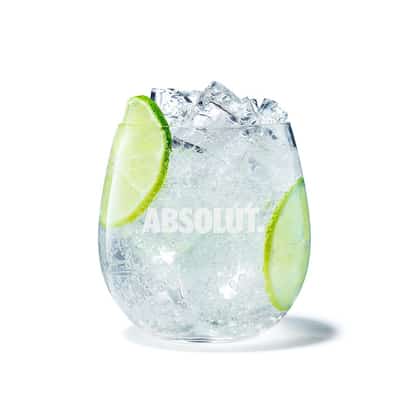 Absolut and Soda in a stemless glass with crushed ice and lime slices on white background