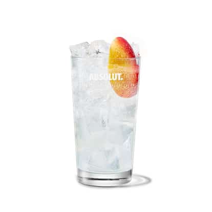 Absolut Apeach Fizz in a highball glass with ice and a peach slice on white background