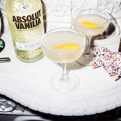 Absolut Asian Ginger in two coupe glasses garnished with lemon twists on white background