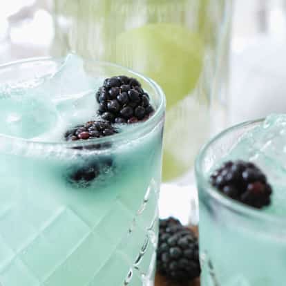Bijou cocktail in a faceted rocks glass with ice and blackberries