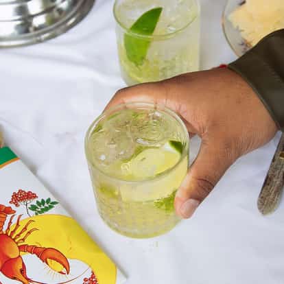 Absolut Buck in a rocks glass held by a hand with ice and a lime wedge