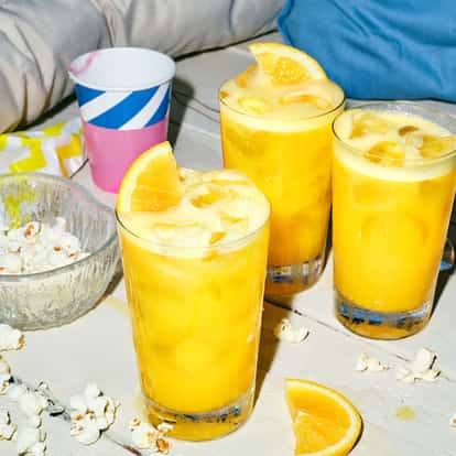 Absolut Fluffy Orange Juice in three glasses with orange wedges and ice on a wooden surface