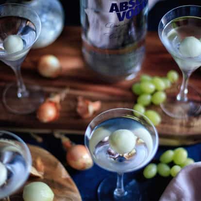 Gibson martini cocktail garnished with a signature pickled onion surrounded by other cocktail glasses