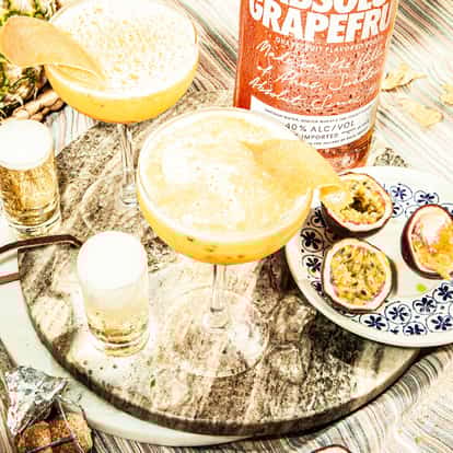 Absolut Grapefruit Passion Star Martini in two coupe glasses with grapefruit peel garnish on striped cloth