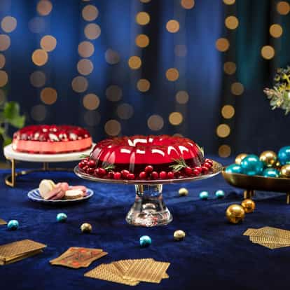 Absolut Jolly Jelly on a glass cake stand with cranberries and rosemary on a velvet tablecloth