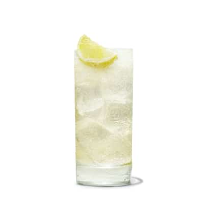 Absolut Juice Pear and Elderflower Soda served in a highball glass with ice and lime wedge on white background
